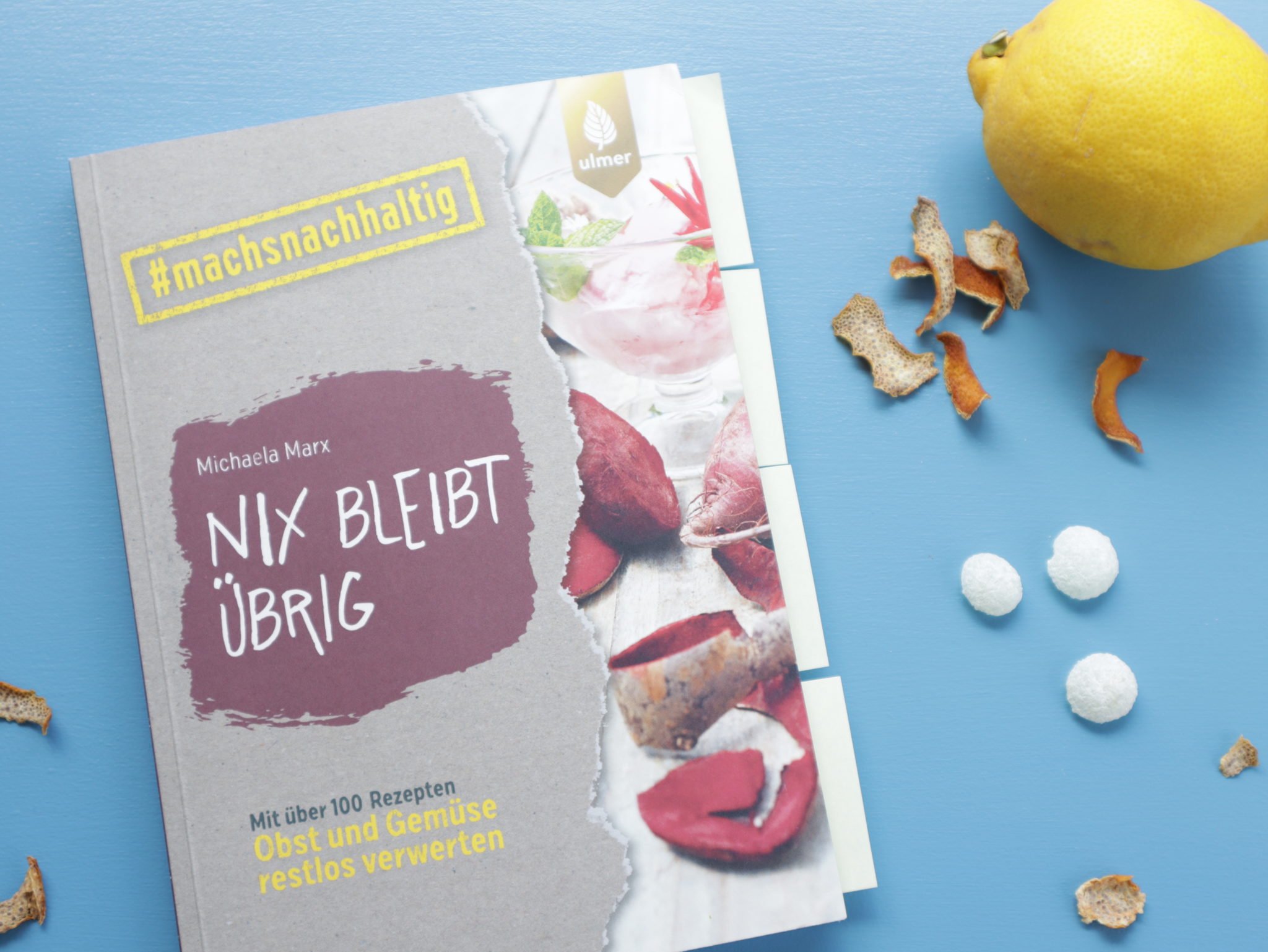 Cover des Buches 'Nix bleibt übrig' sowie selbstgemachte Zitronenbonbons, getrocknete Zitronenschalen und eine Zitrone.