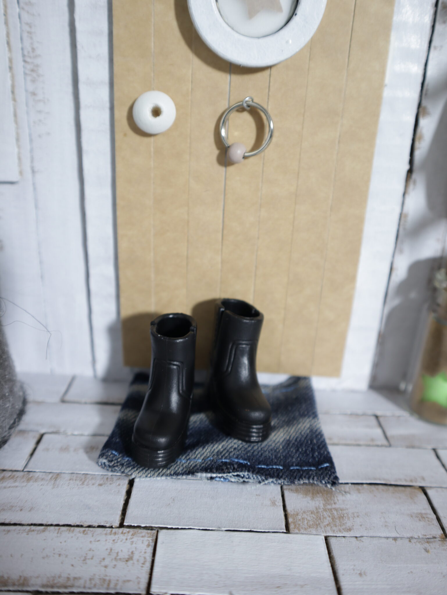 Schwarze Stiefel stehen vor der Wichteltür auf einem Fußabstreifer aus Jeans.