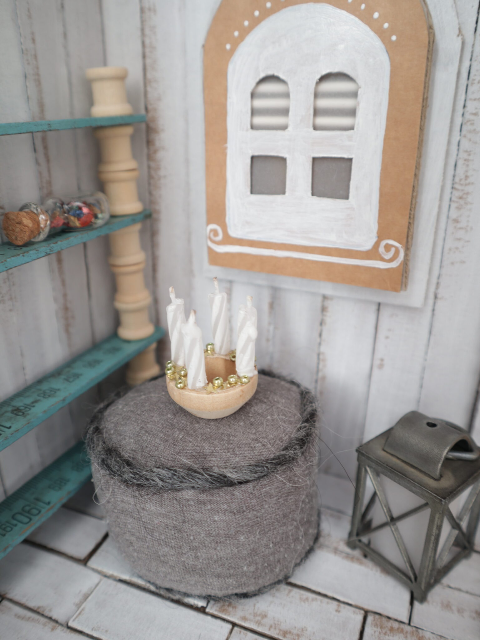 Mini-Adventskranz mit kleinen Stummeln ehemaliger Geburtstagskerzen auf einem Holzring. Der Kranz steht auf einem Mini-Sitzkissen.