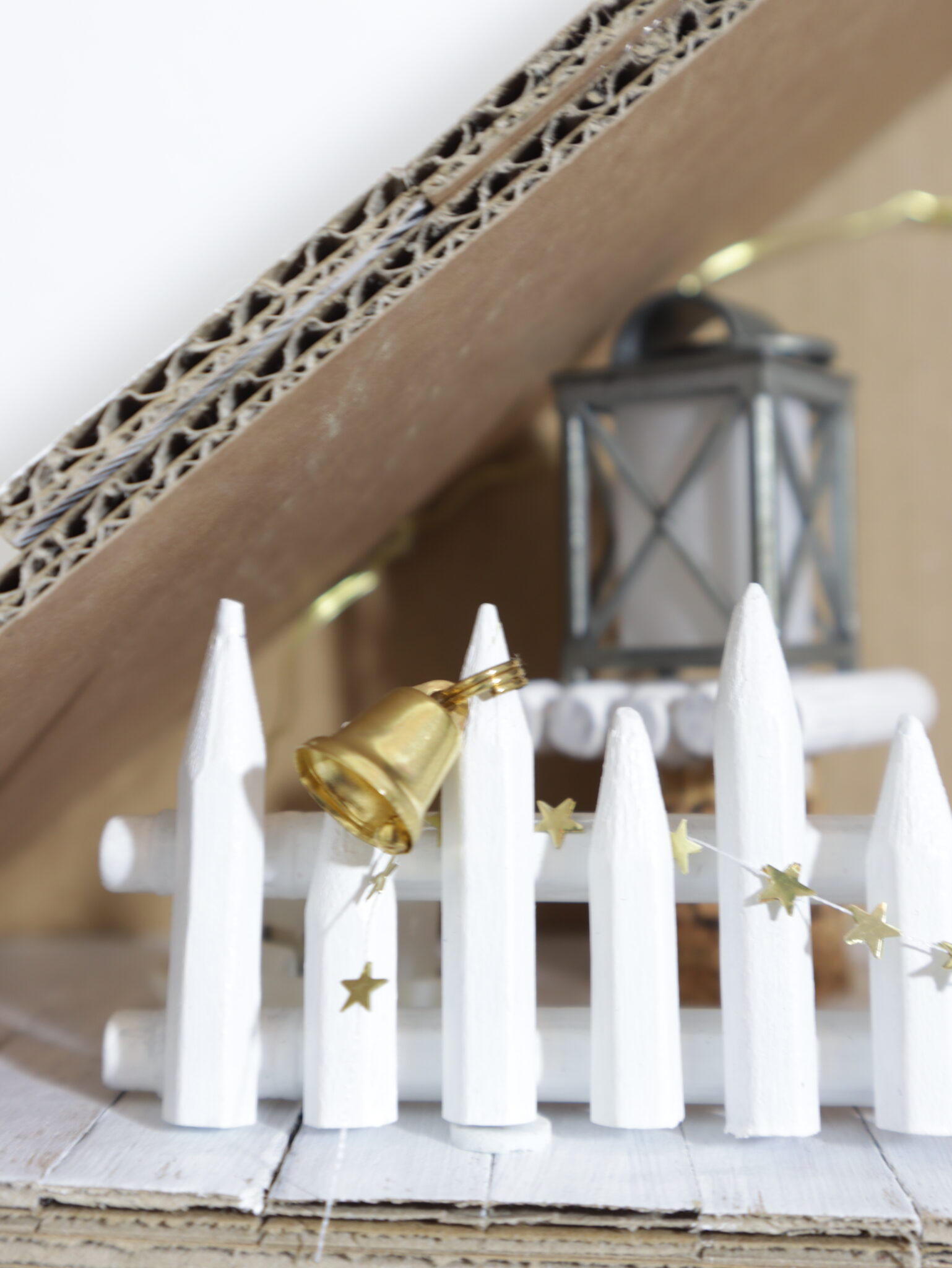 An der Brüstung aus Buntstiftresten hängt eine goldene Glocke sowie eine Girlande aus goldenen Sternen.