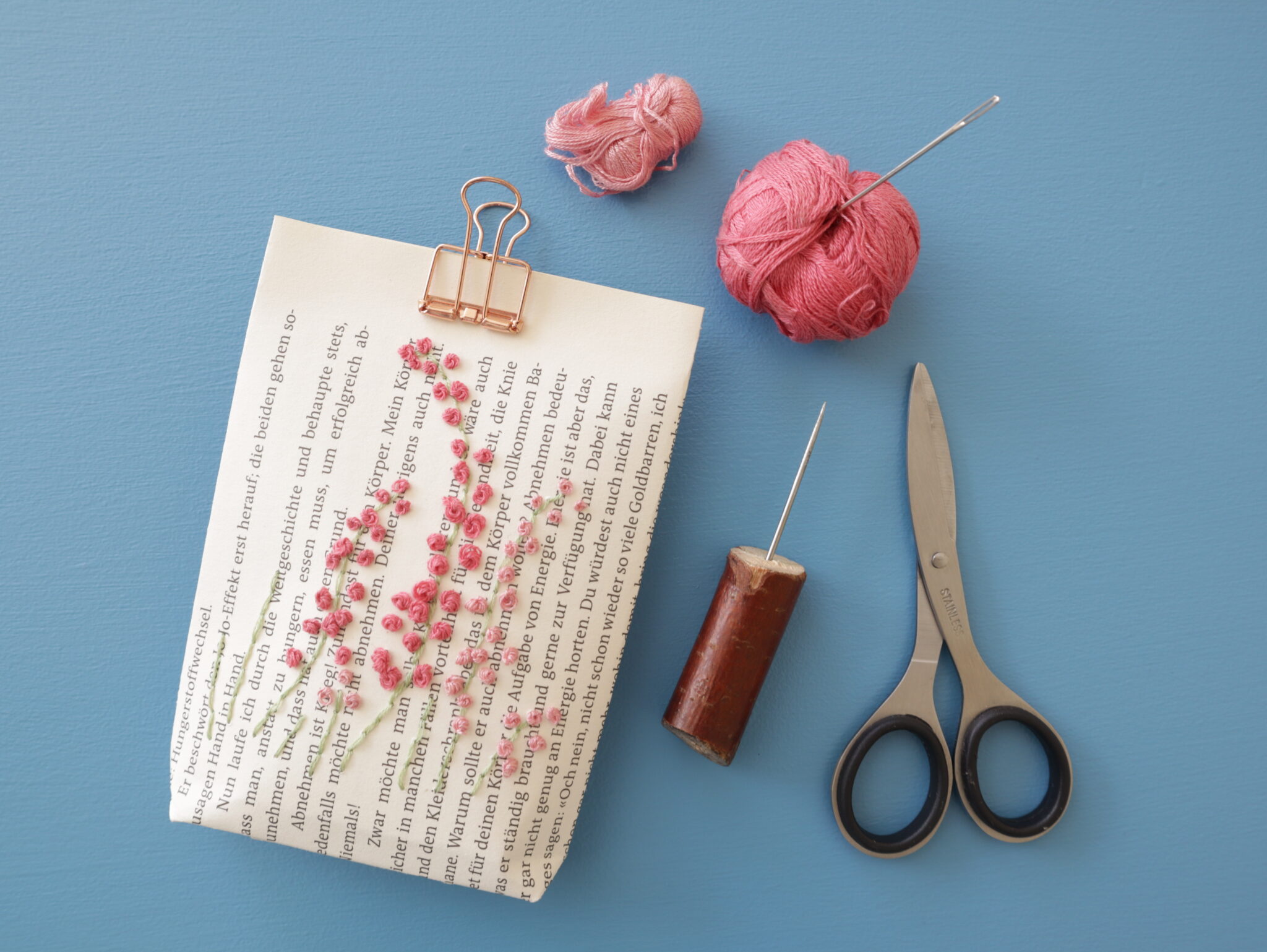 Papiertüte aus einer alten Buchseite, bestickt mit Blüten aus Knötchenstichen.